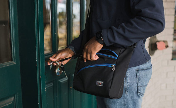 A person unlocking a door with keys attached to the Icon with a key strap.